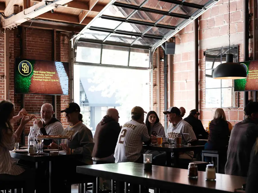 Baseball fans enjoying a bite with open garage doors at Far Corner