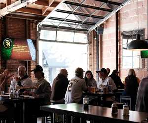 Baseball fans enjoying a bite with open garage doors at Far Corner