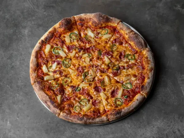 Big Island Pizza topped with pineapple and jalapeño, overhead on concrete