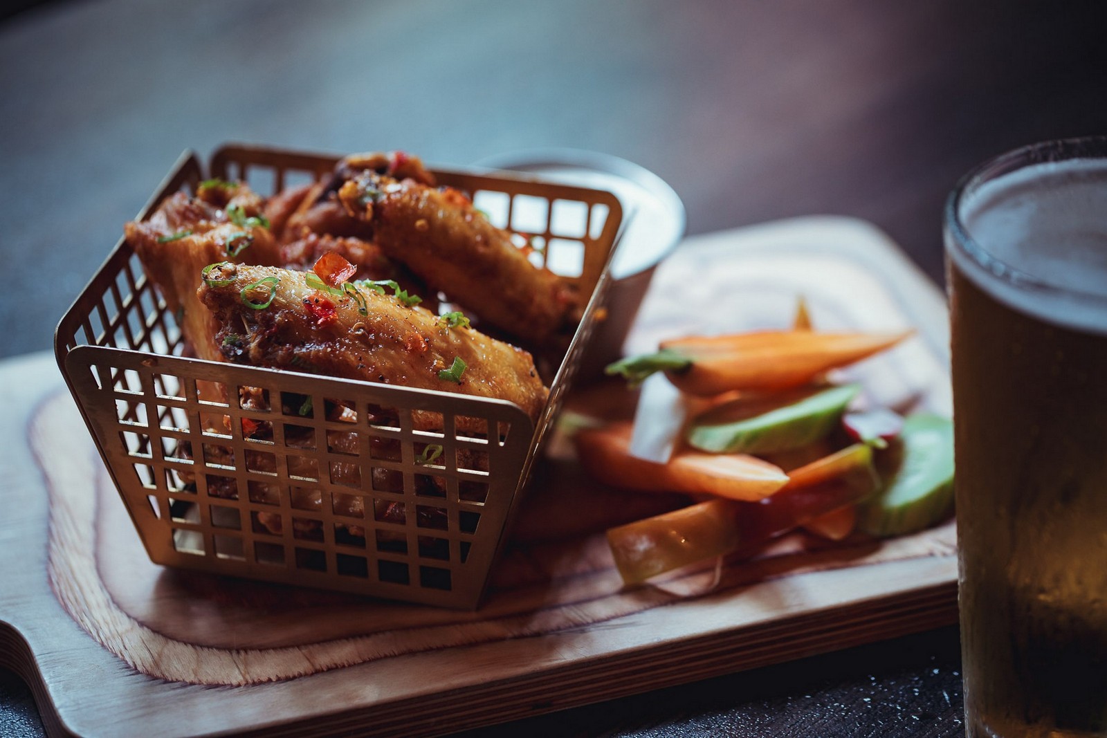 Small-batch wings and a cold draft beer on a wooden board
