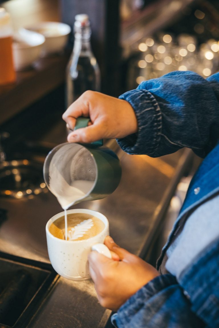 Barista pouring steamed milk for a latte at the Far Corner café