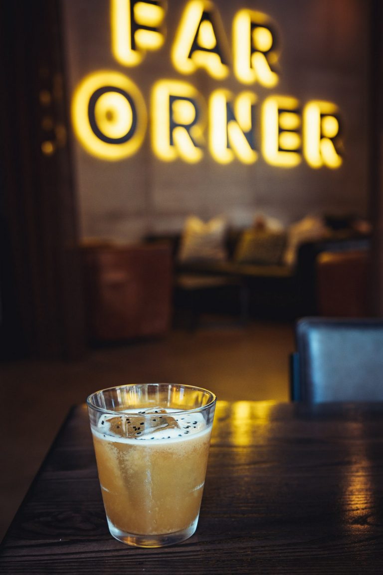 Cocktail in front of the Far Corner neon sign